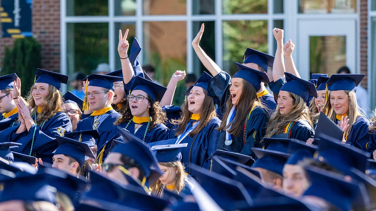 line of graduates cheer after being awarded their degrees