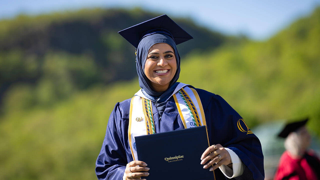 A graduate smiling with her diploma