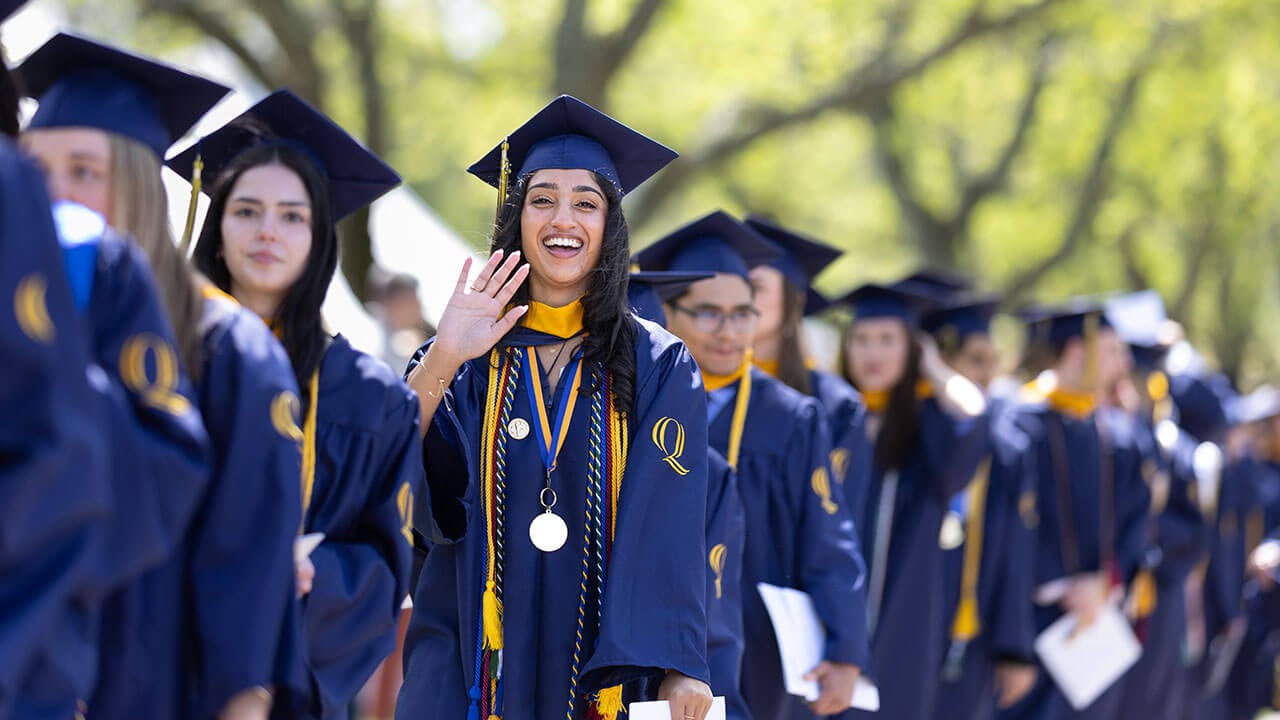 A graduate waves as she processes in