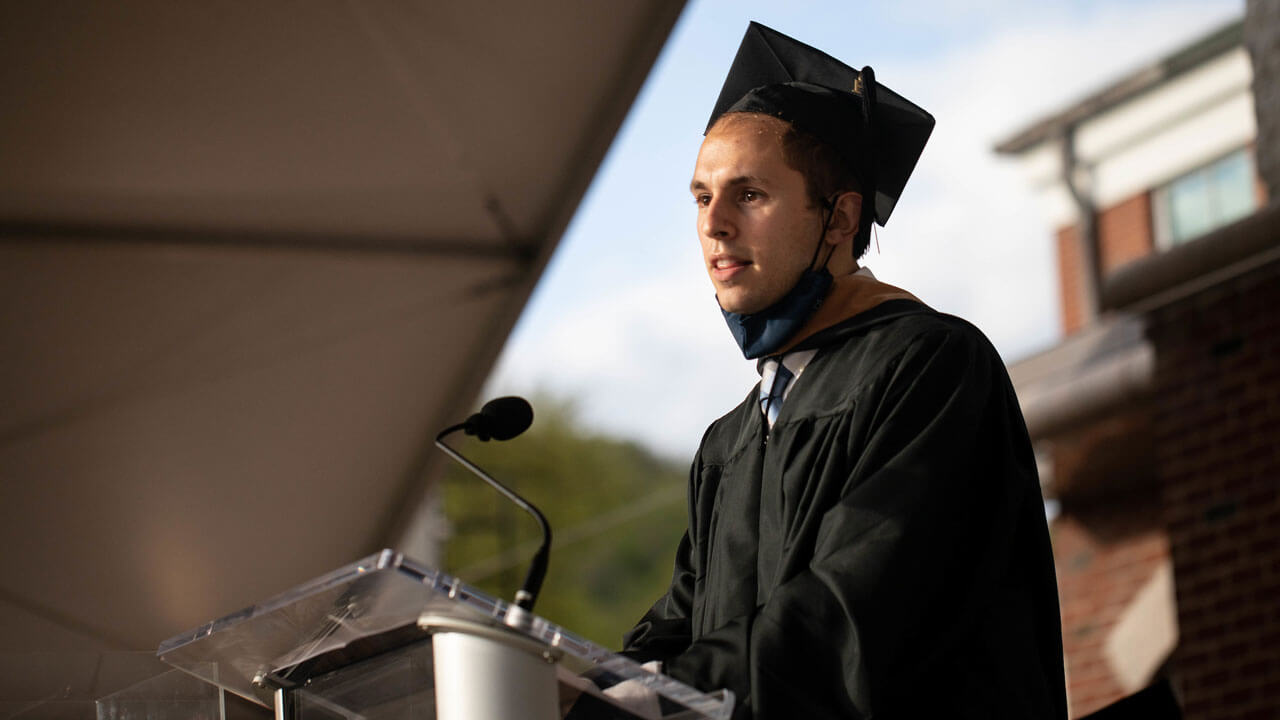 Gregory Tack speaks at the podium as the sun sets