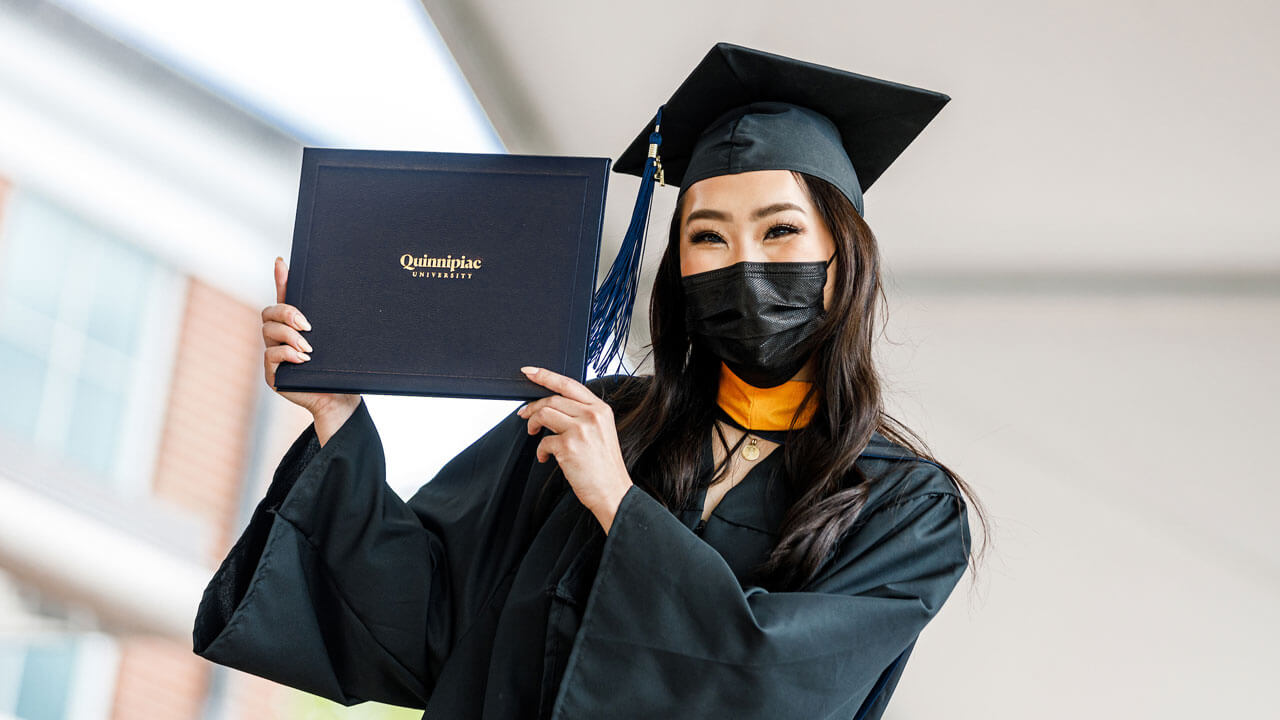 A graduate poses for a photo as she walks across the Commenecment stage