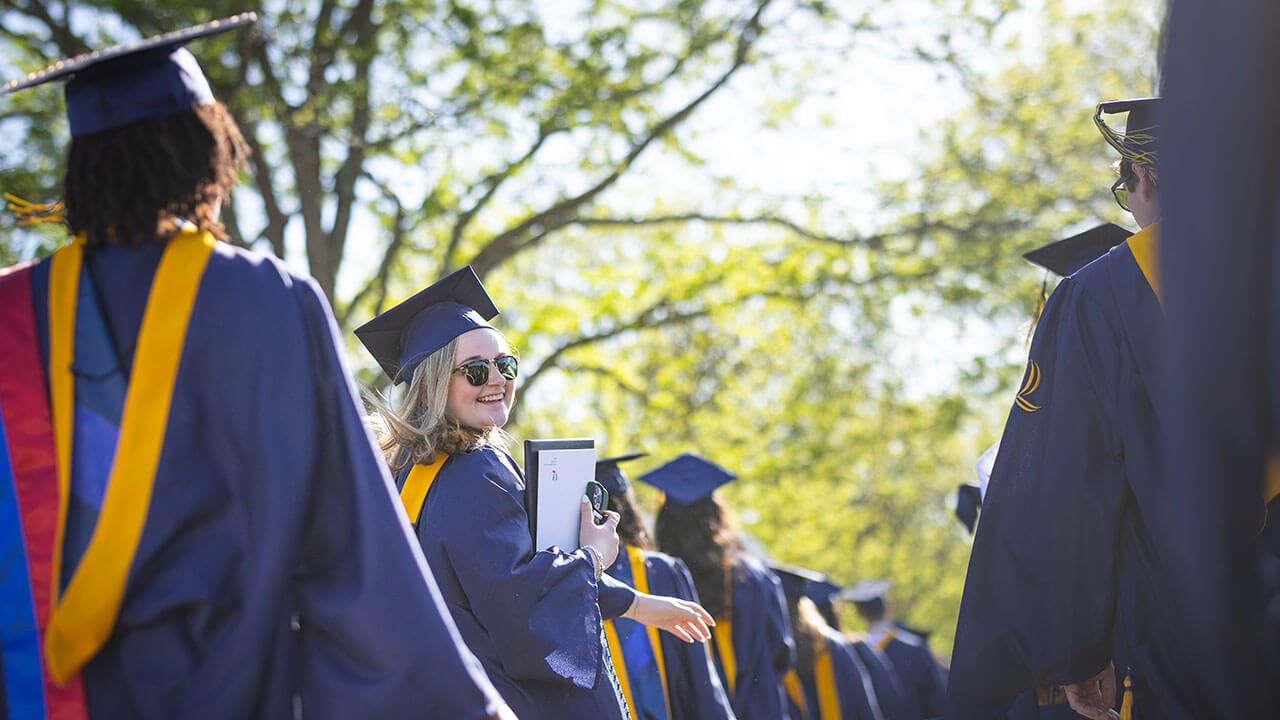 graduate looks back and smiles at the camera