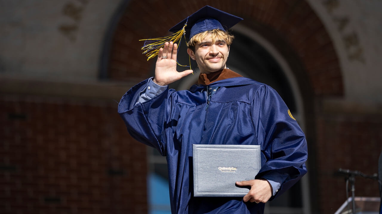 Graduate waves to the crowd after accepting their diploma.