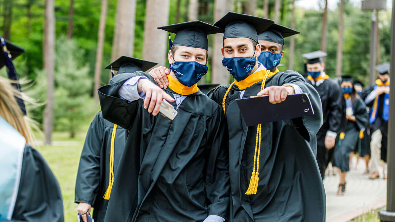 Two graduates pose together as they wait for their turn to walk to the ceremony