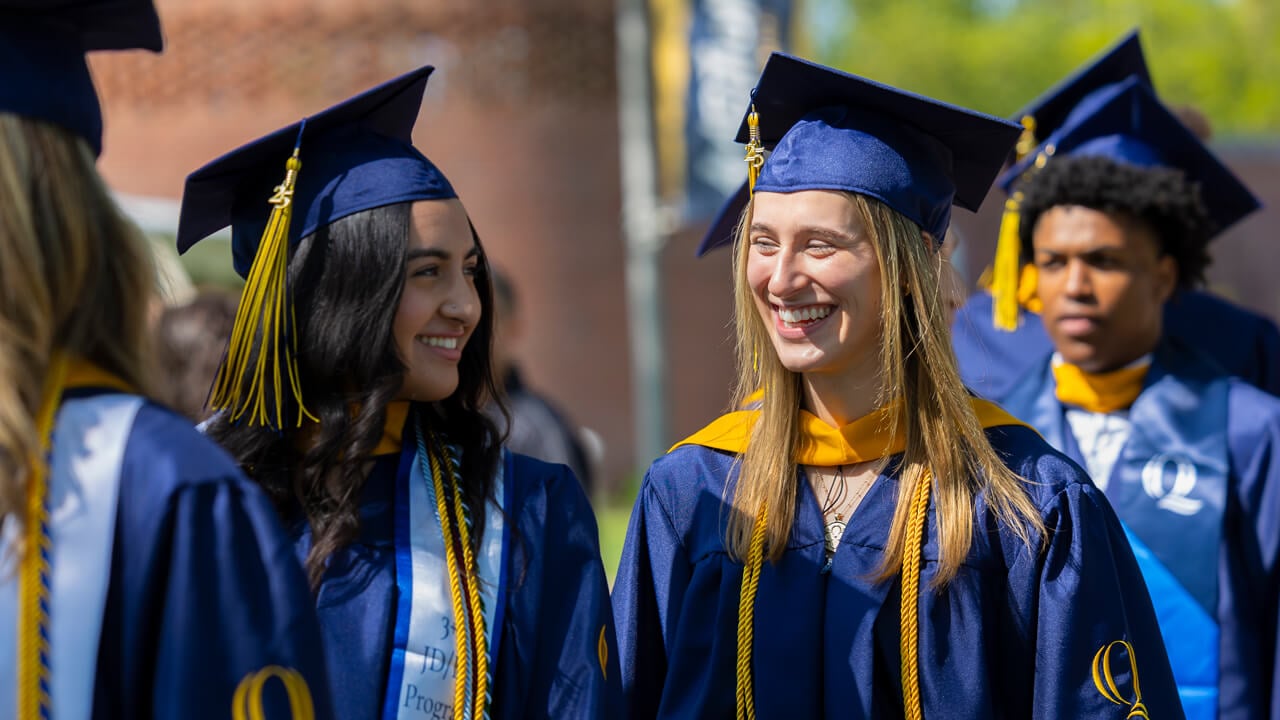 Graduates smile at each other as they process into commencement.
