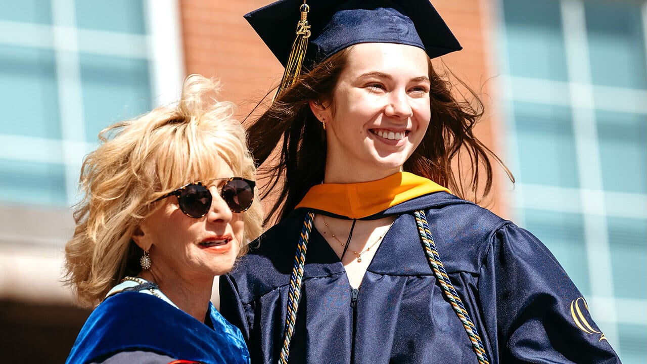 President Judy Olian smiling with a grad on stage