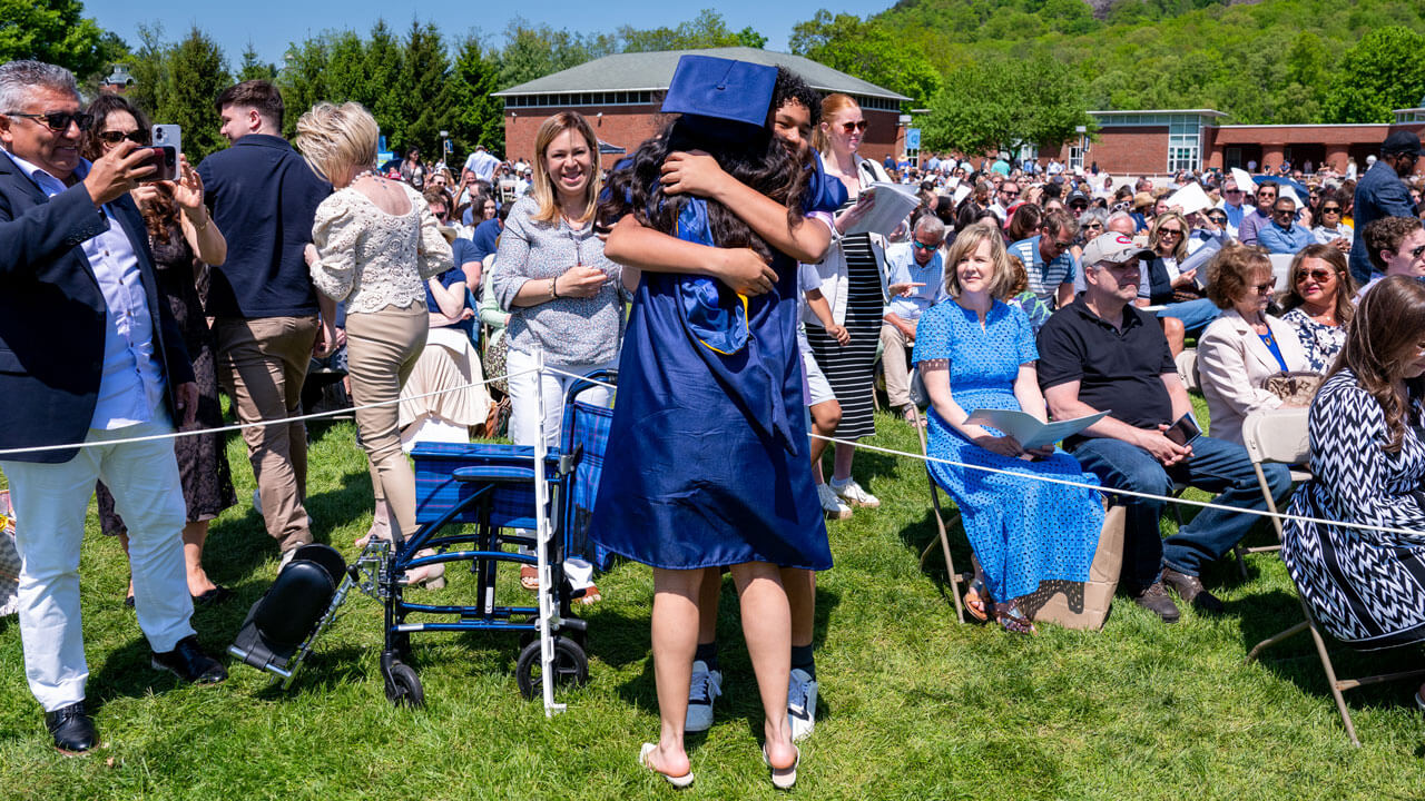 Graduate hugs their loved one as others take photos.