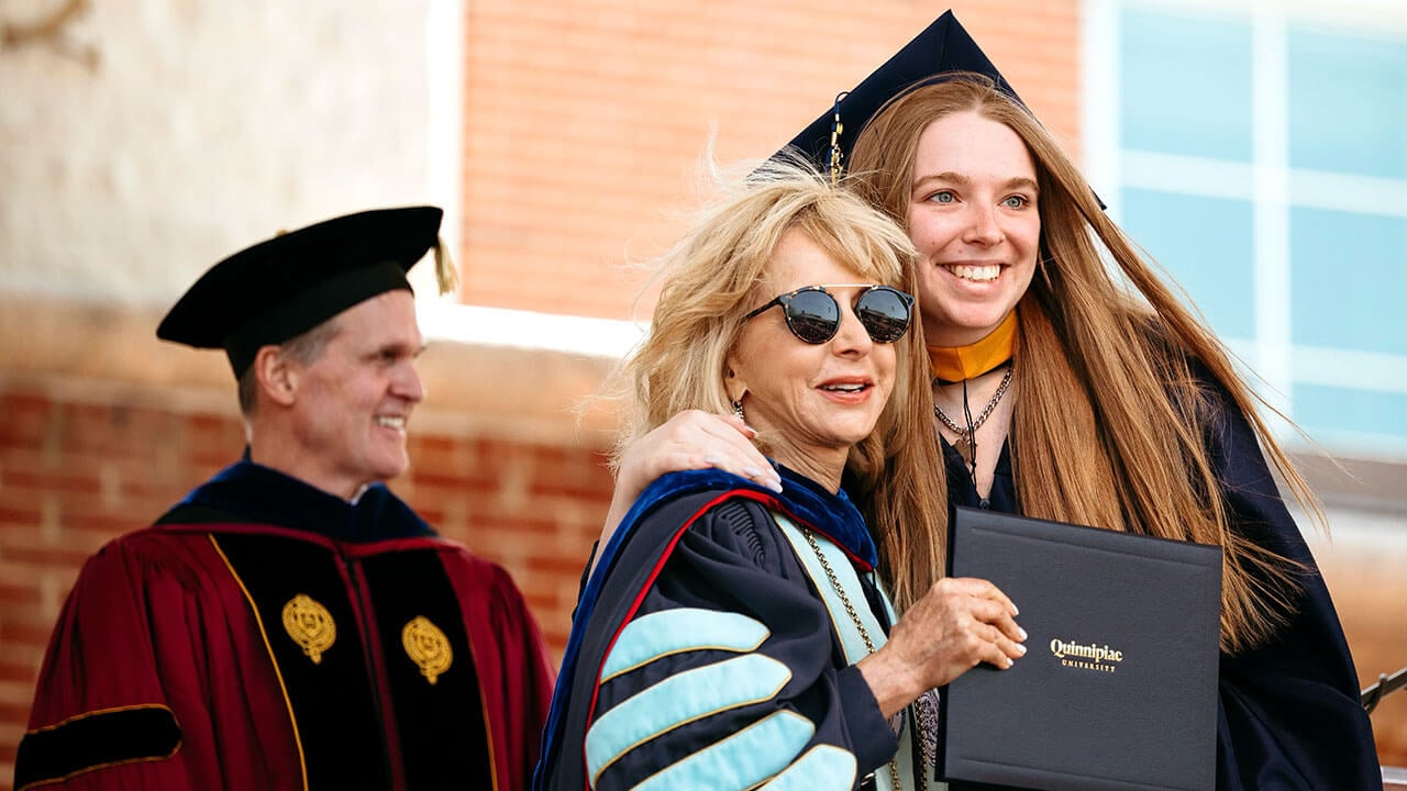 President Judy Olian smiling with a student on stage