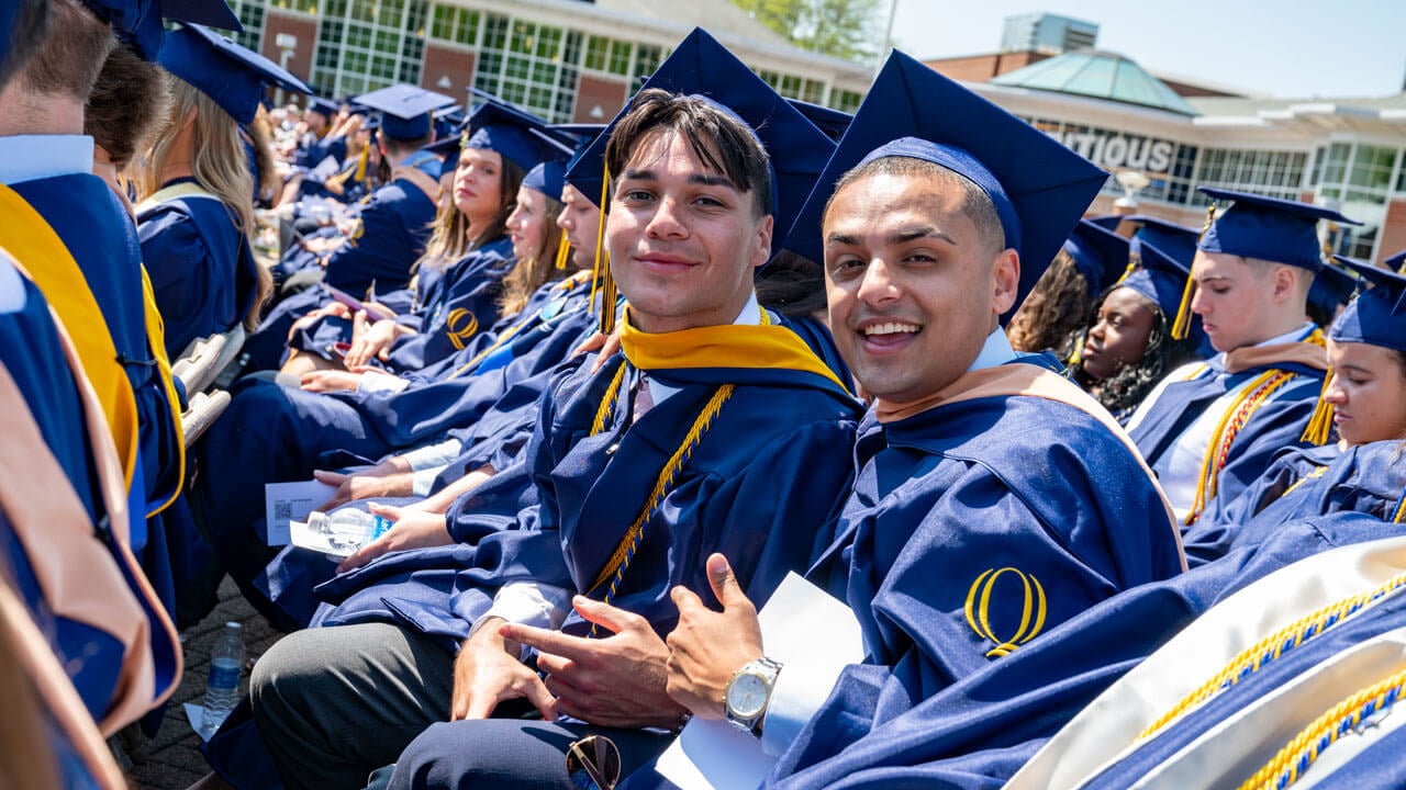 Graduates smile from their commencement seats.