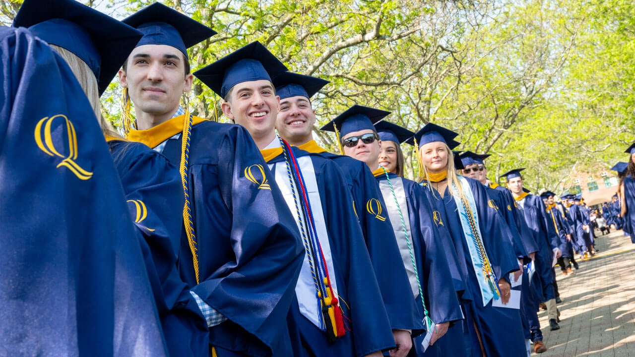 Graduates smile as they process into commencement.