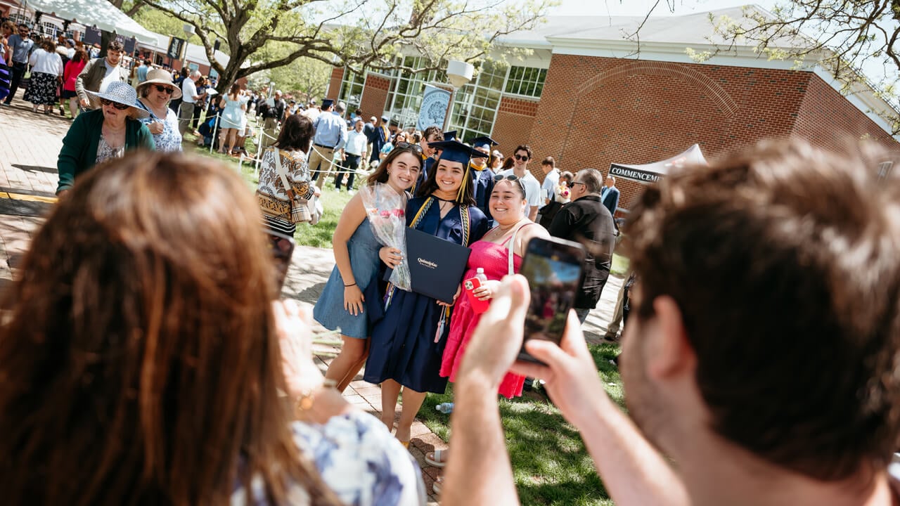 Graduate poses with their loved ones, diploma in hand.