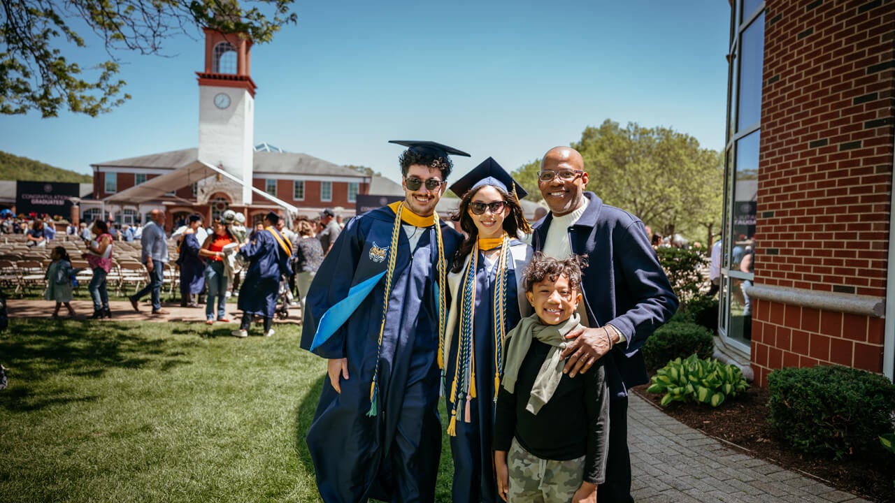 Graduates and their family members smiling in front of Arnold Bernhard library.