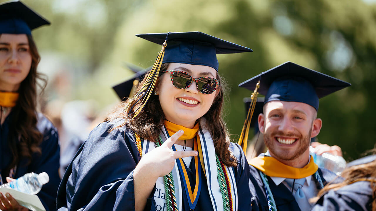 A graduate throwing up a peace sign