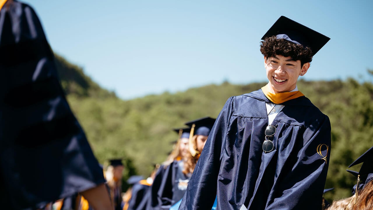 A graduate smiling as they process in