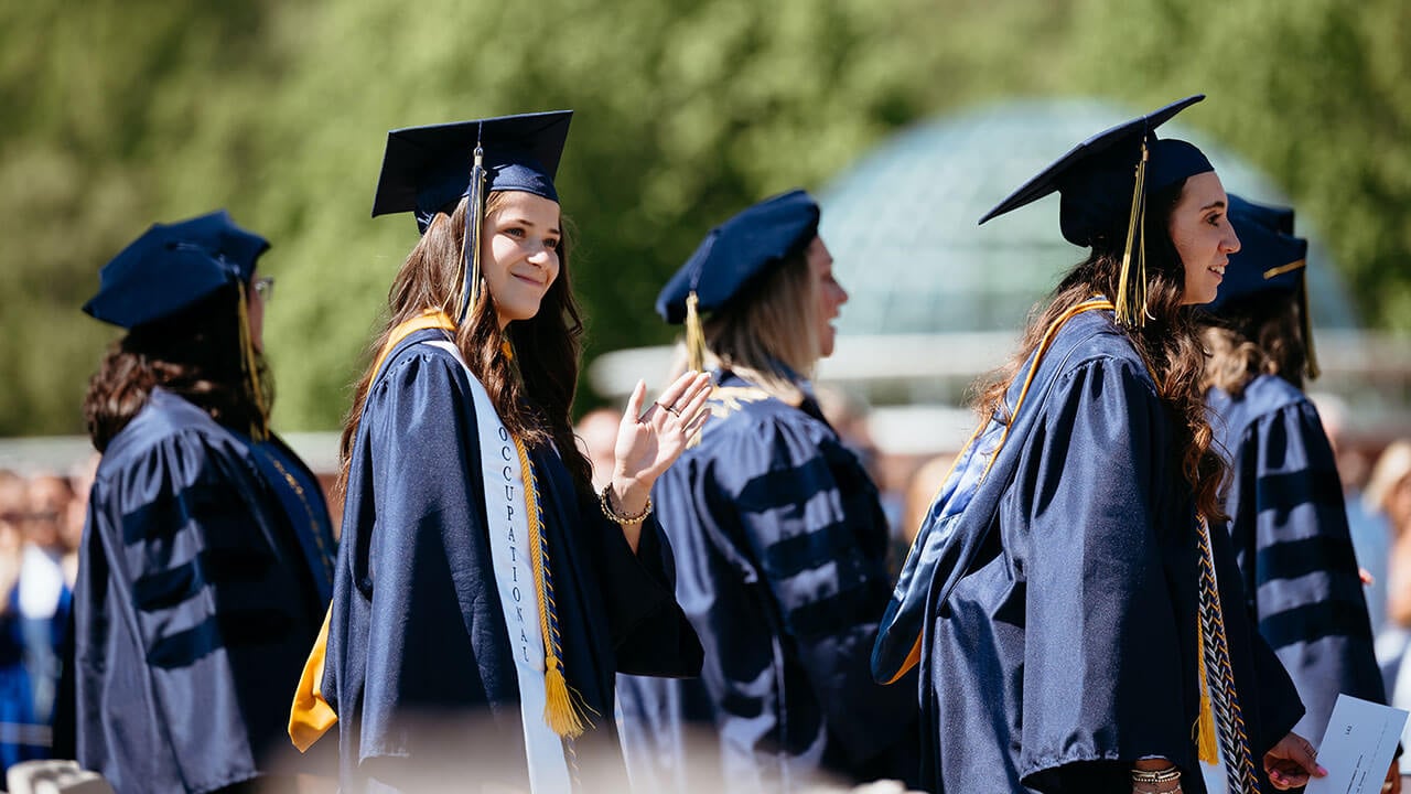 A grad walking onto the quad and waving