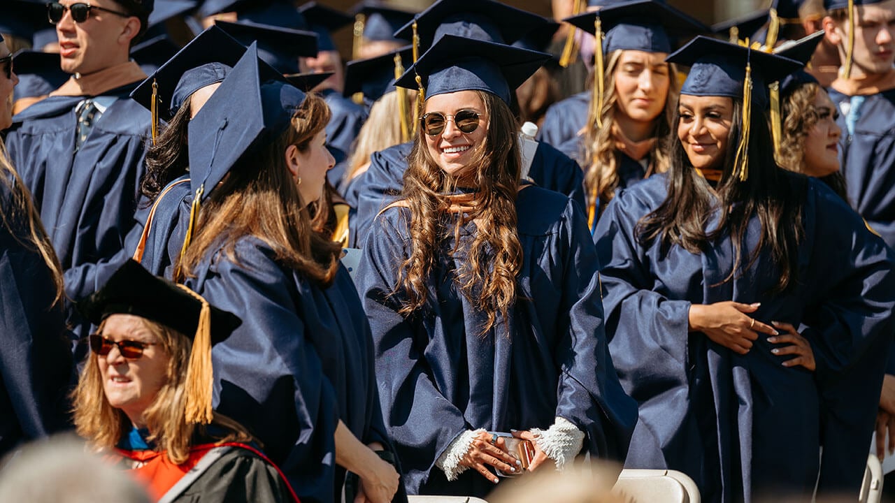 Graduates smiling at one another.