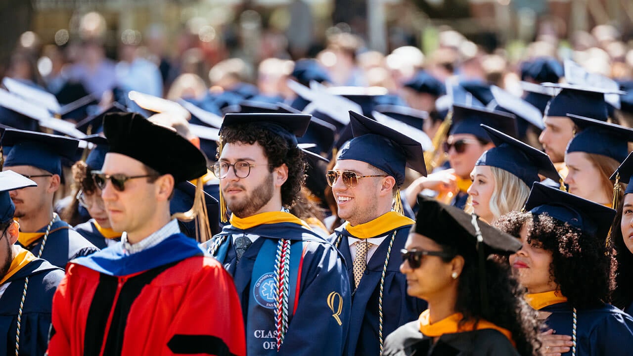 A group of graduates sit on the quad for commencement