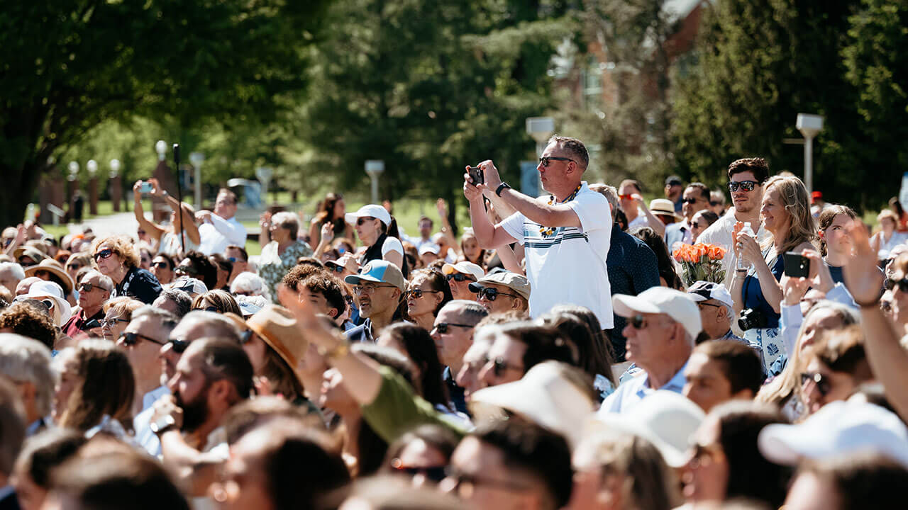 A crowd member standing up to take a photo