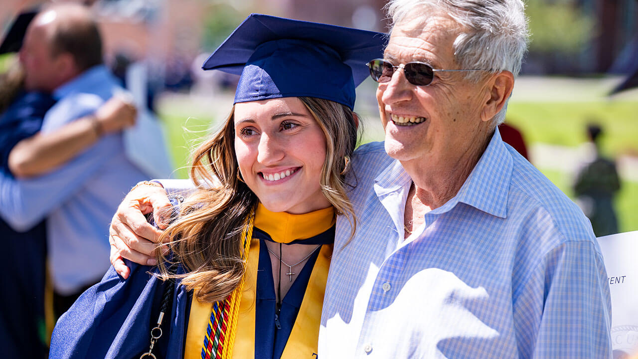 A graduate posing for a group photo with a family member