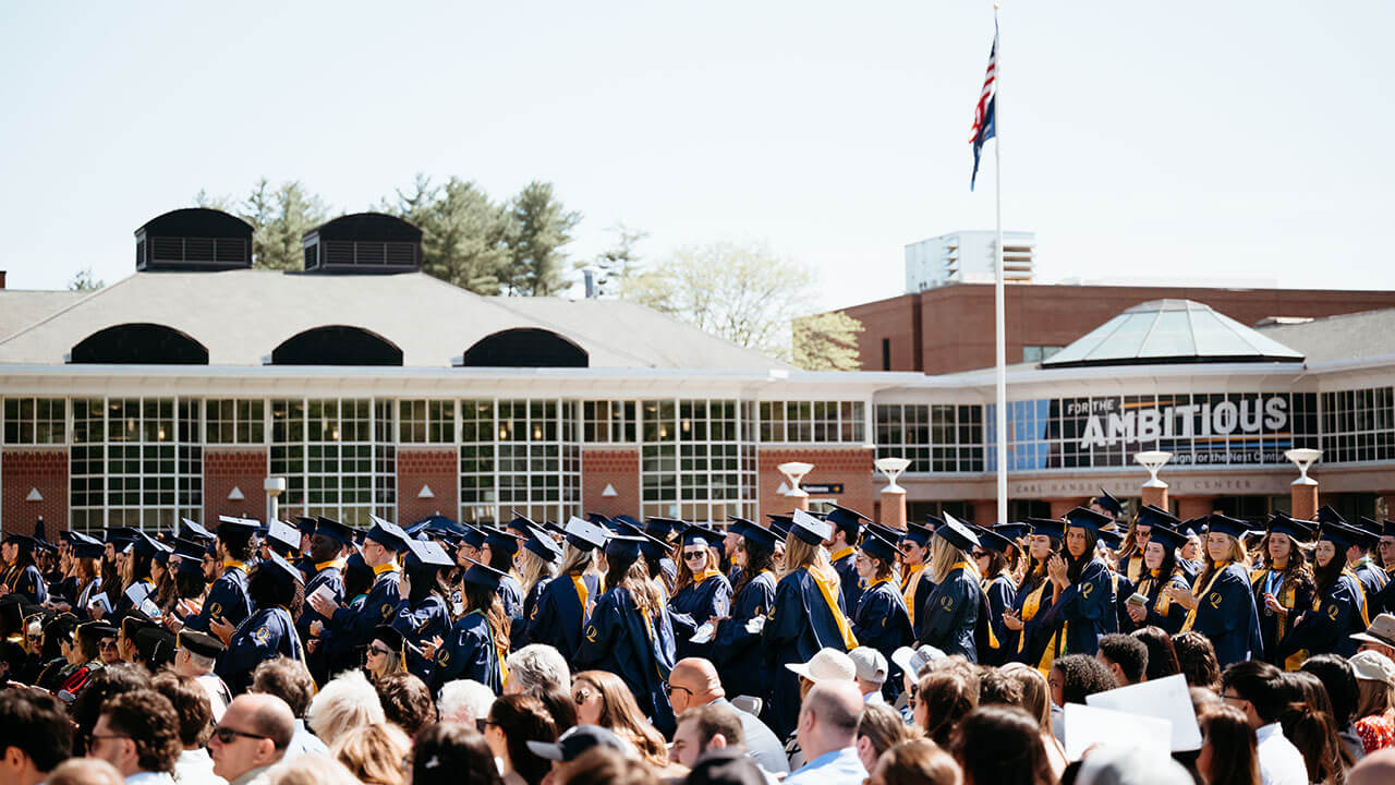 Grads standing up on the quad in front of their student center