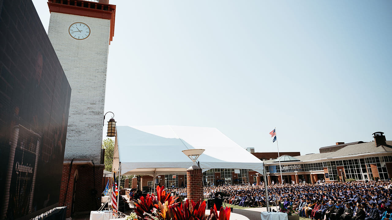 Arnold Bernhard Library with graduates sitting on the quad
