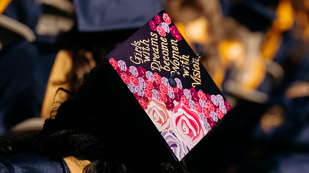 A cap that says "girls with dreams become women with vision"