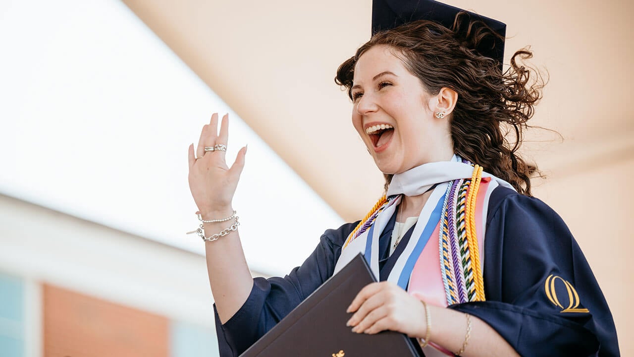 A graduate waving as they walk off stage
