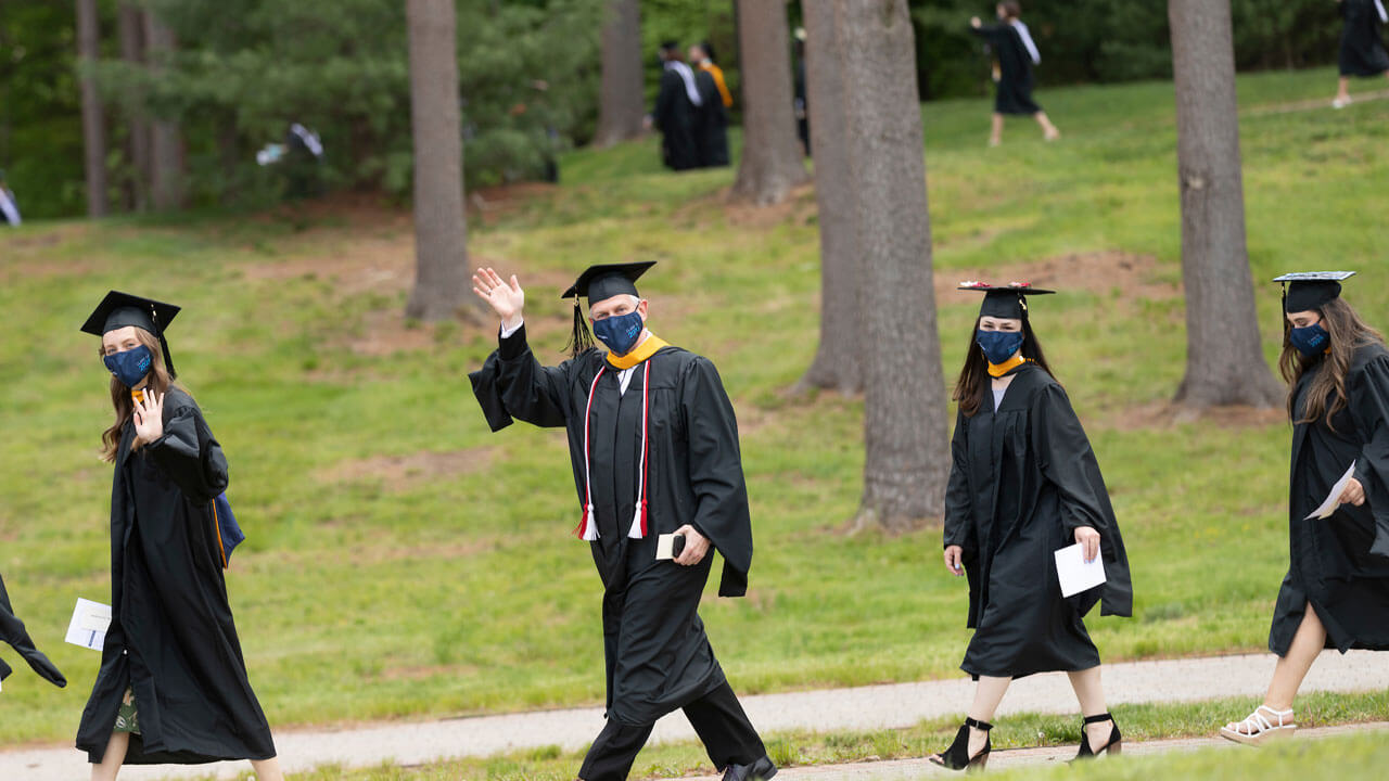 Brian Koonz waving while walking through the pine grove