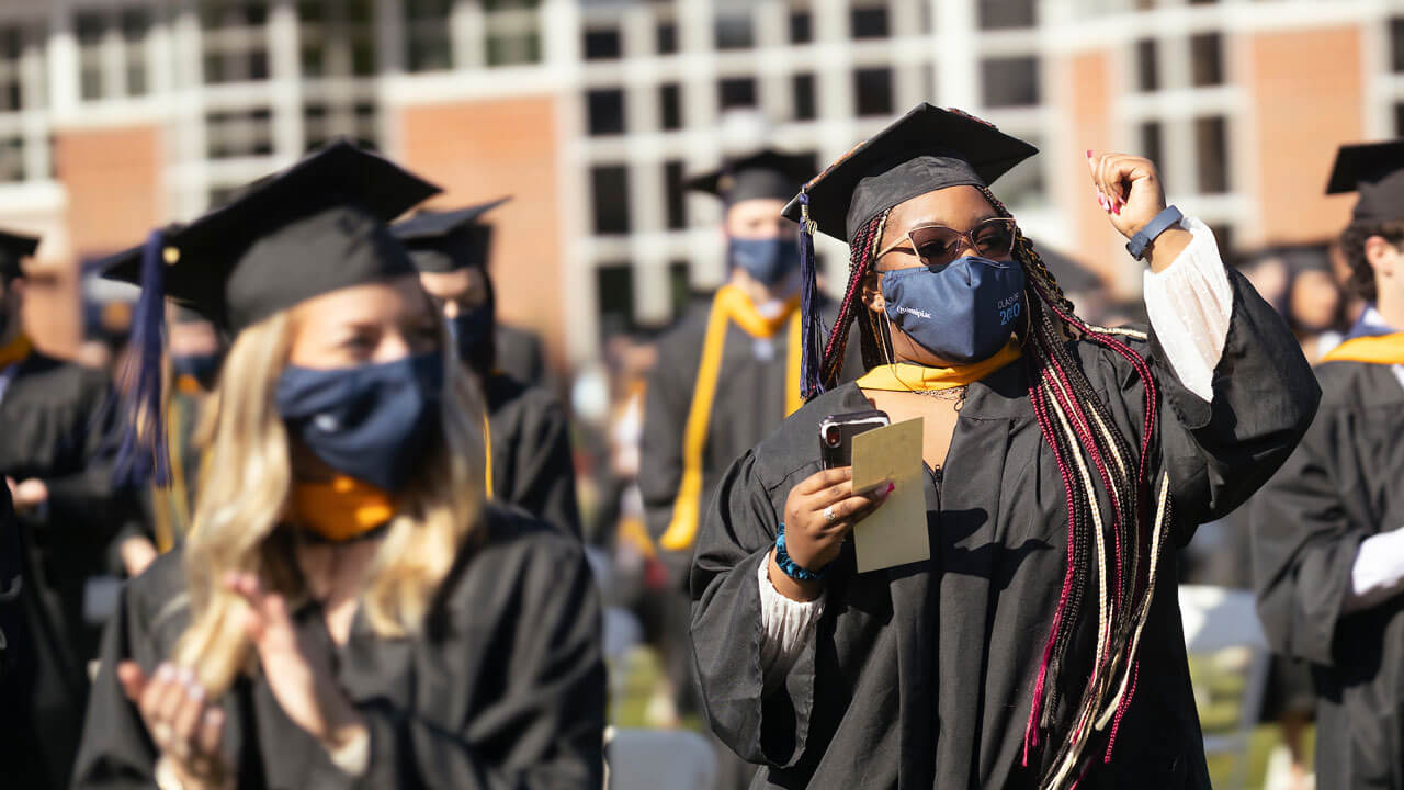 Several graduates cheer from their seats on the quad