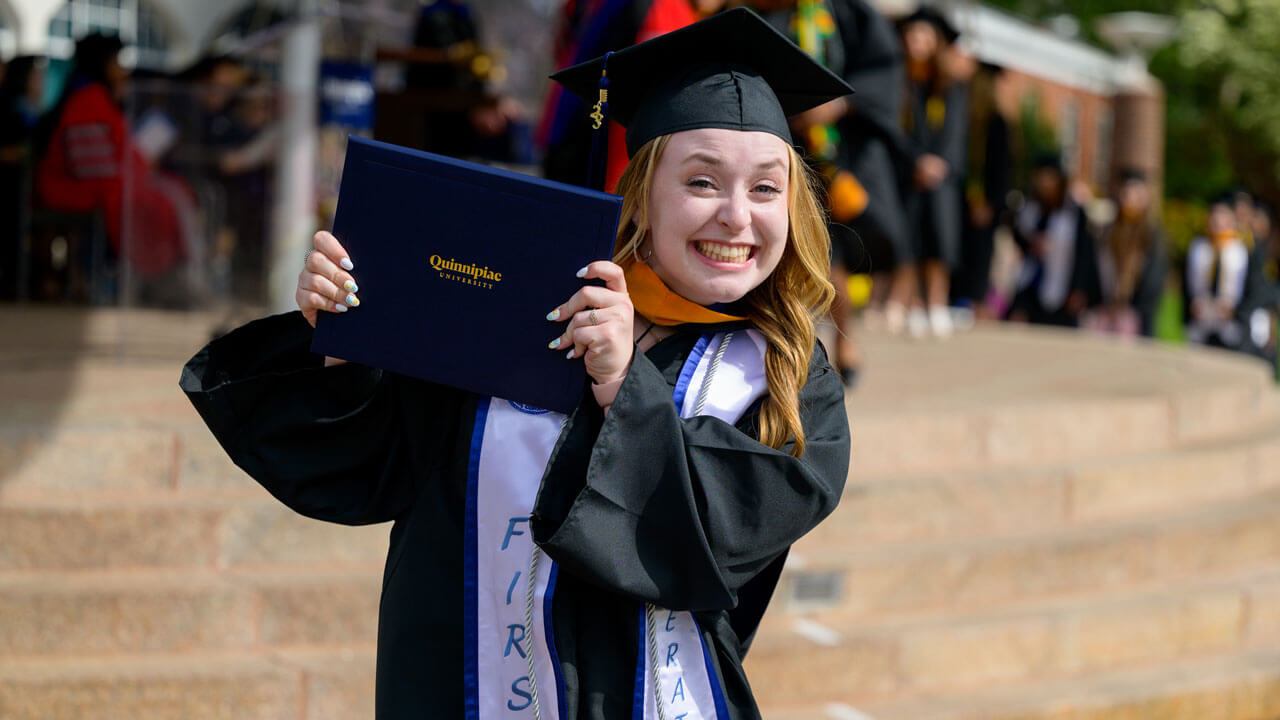 Graduate smiles holding diploma