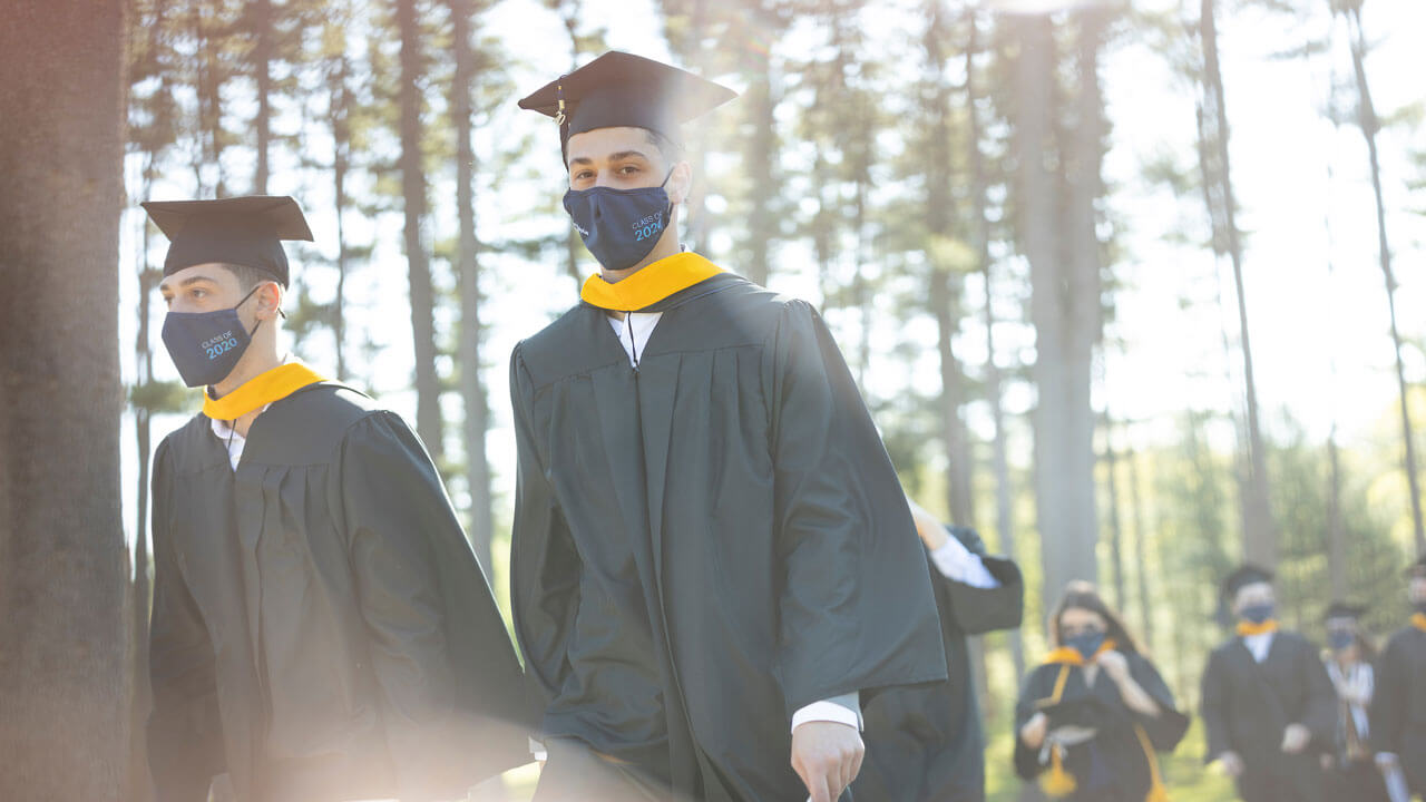 2020 graduates walking through the pine grove