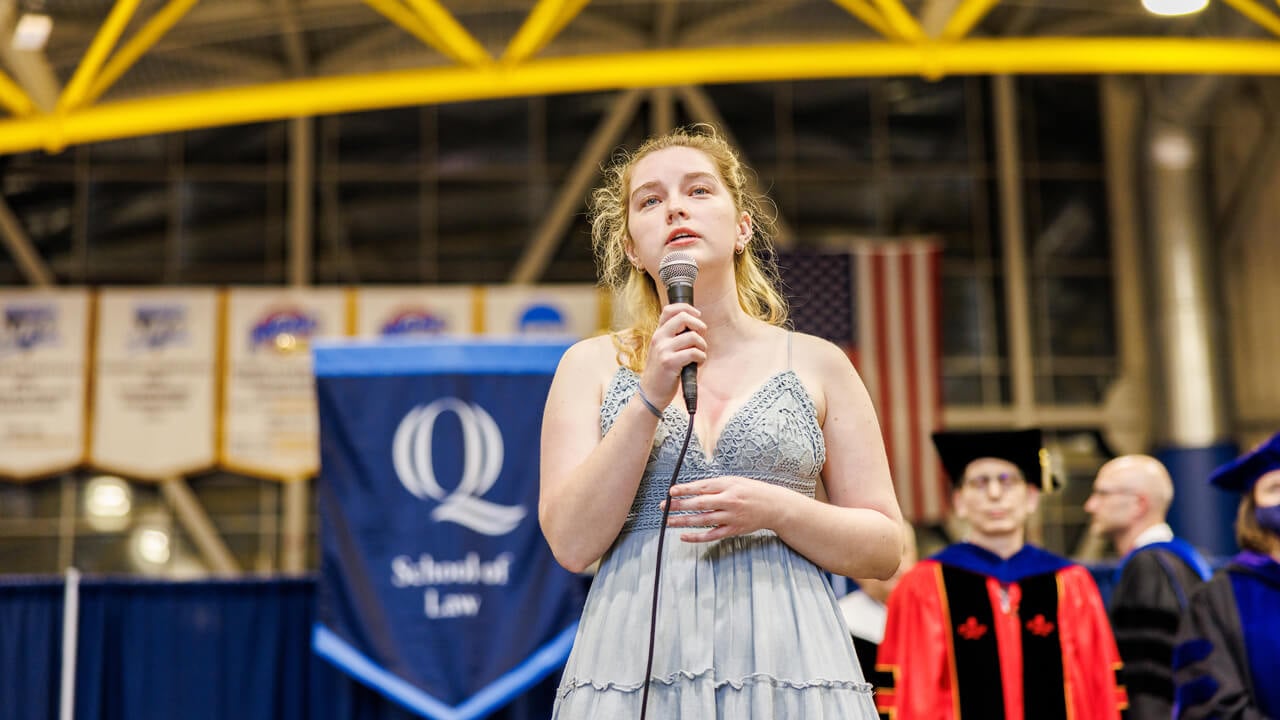 Krista Hall sings the national anthem with a microphone onstage