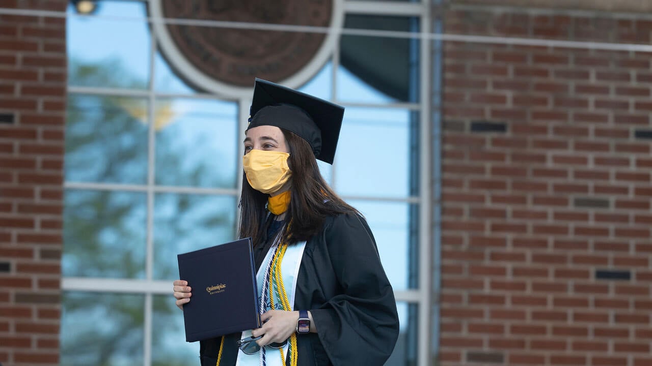 Graduate holding her diploma on the stage