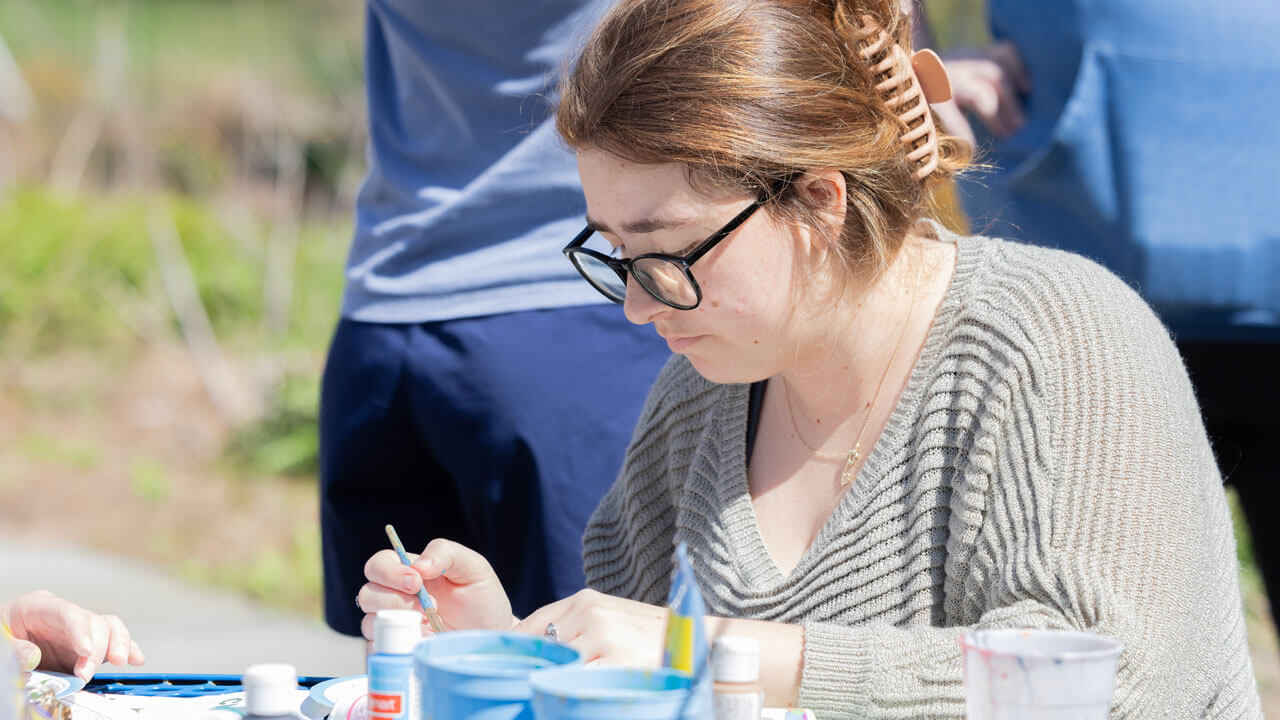 Quinnipiac Arbor Day volunteer paints rocks for garden