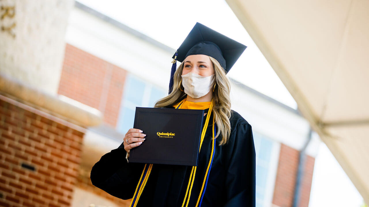 Graduate walking across the stage holding their diploma