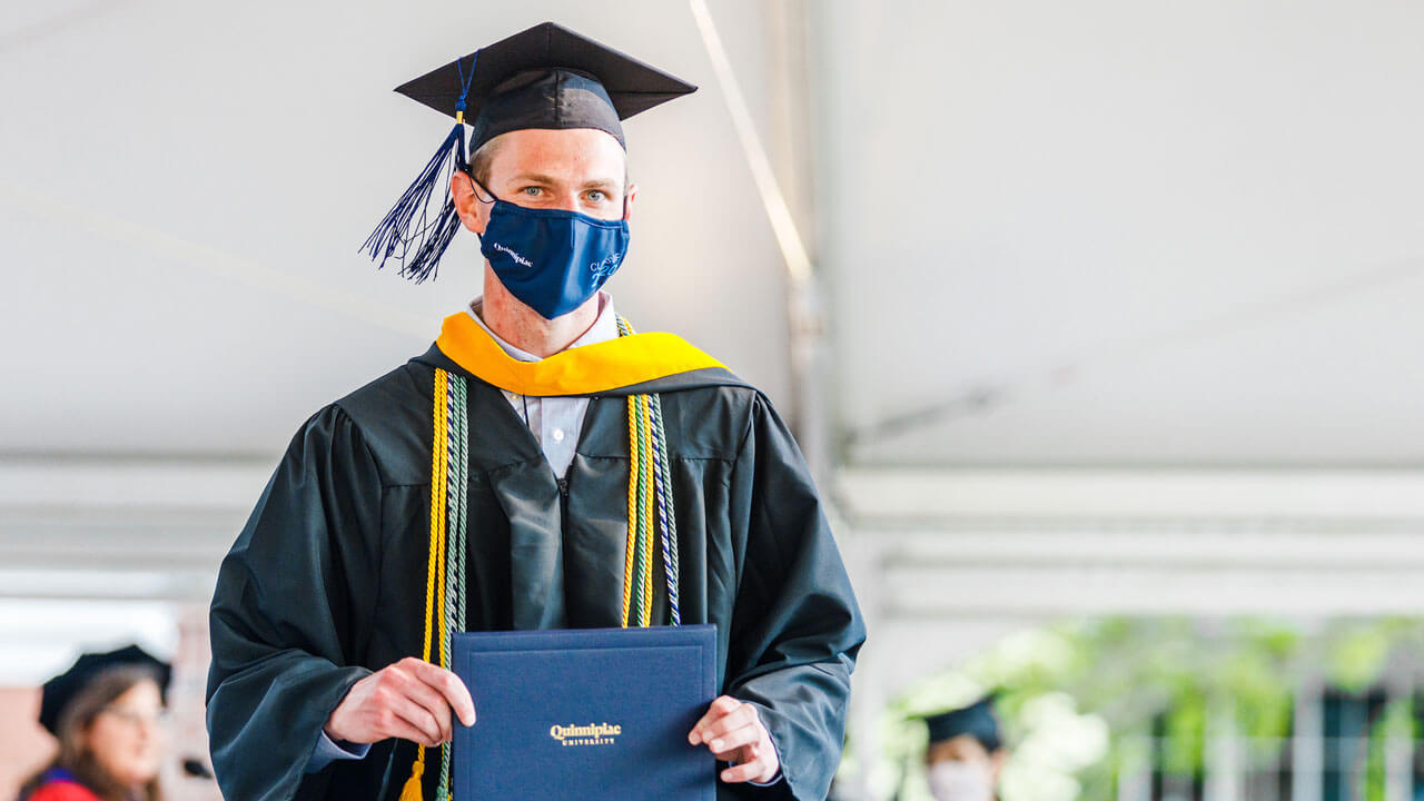 Graduate walking across stage with diploma