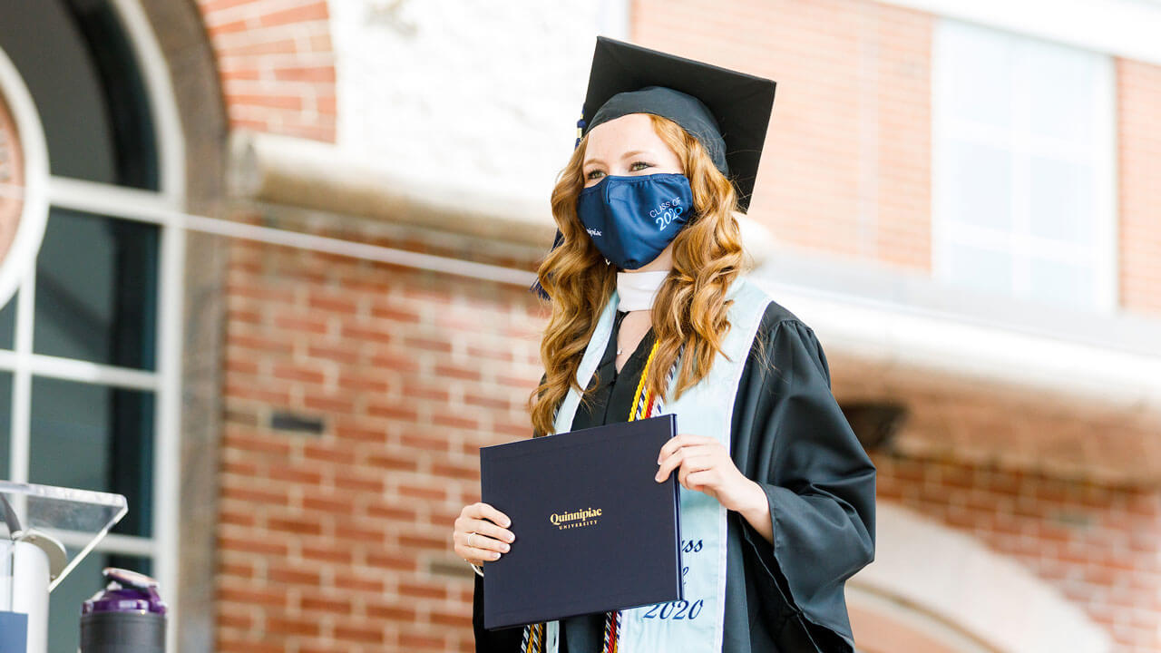 Graduate holding her diploma on the stage