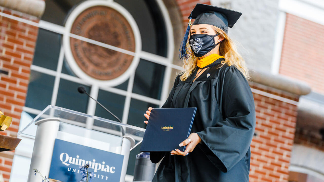 Student displaying diploma at commencement ceremony