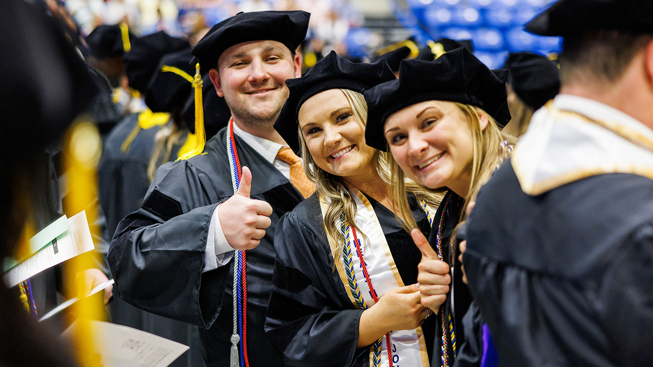 Graduates give thumbs up to the camera