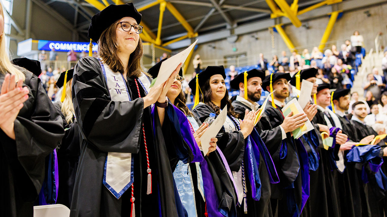 Graduates clap while standing for the professional oath