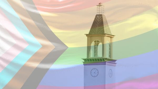 The Arnold Bernhard Library clocktower seen through a translucent progress pride flag waving in the air