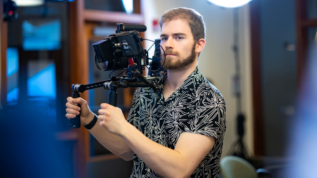Student holding a camera, recording a scene