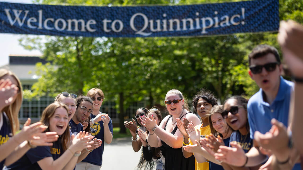 Students clapping and cheering in front of a banner