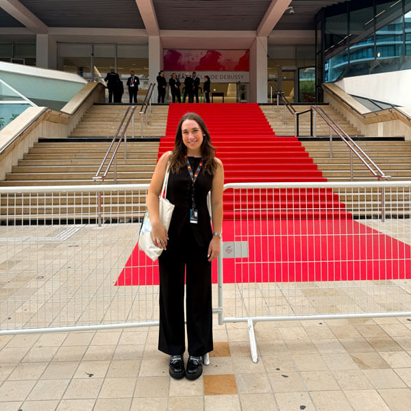 Individual stands in front of the Cannes Film Festival red carpet.