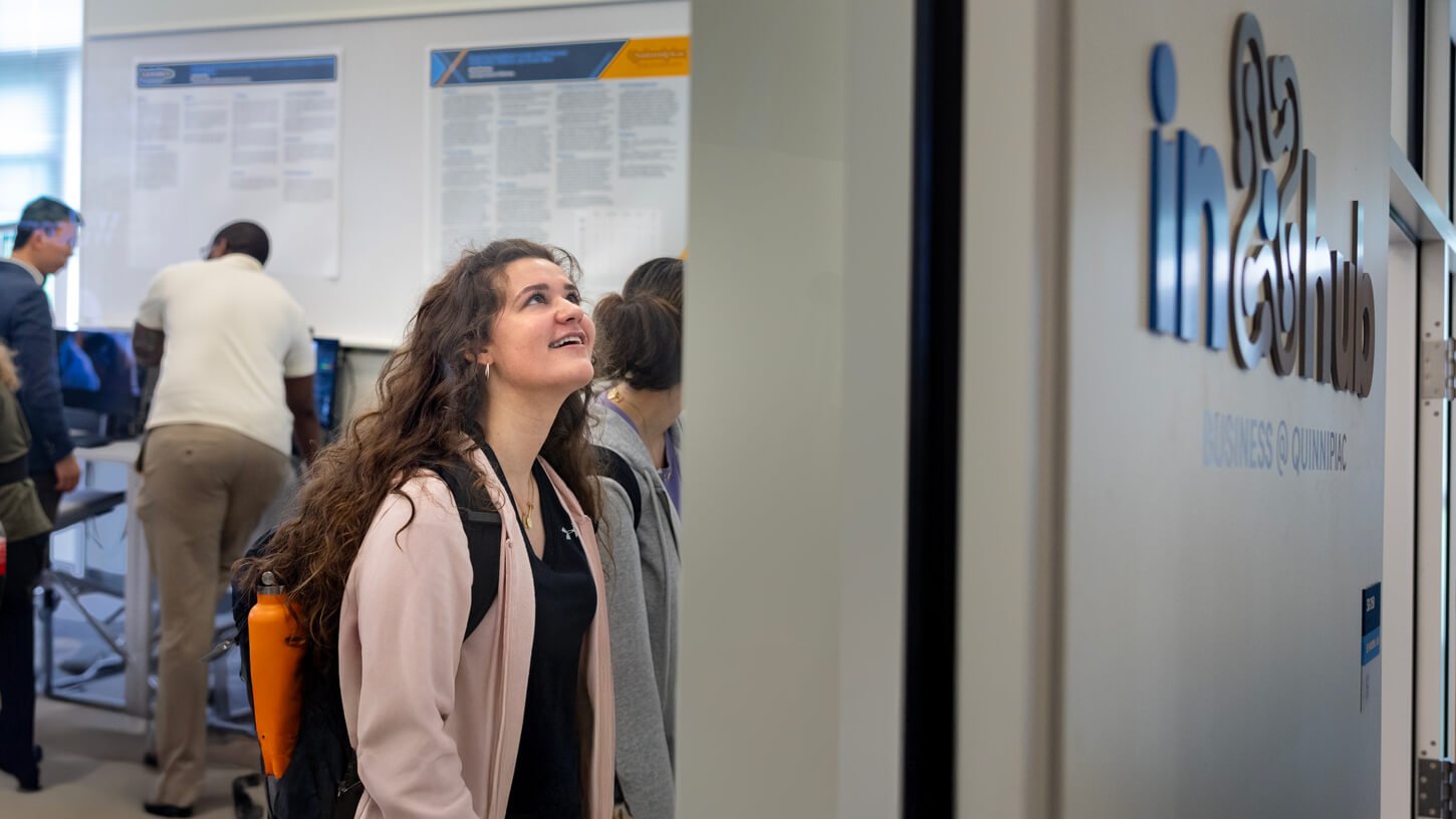 A student presents a research poster titled “Consumer Response to AI Transparency in the Context of Recommendation Systems” to a faculty member