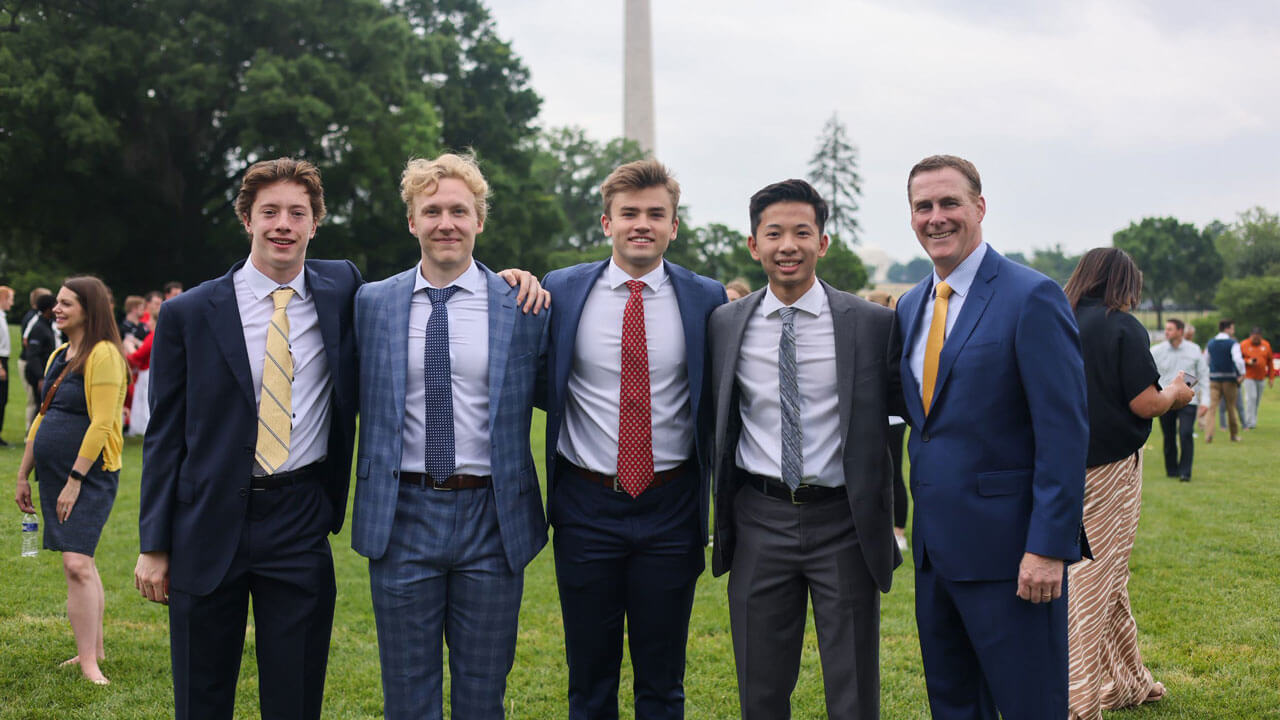 Hockey team smiling with coach Rand Pecknold