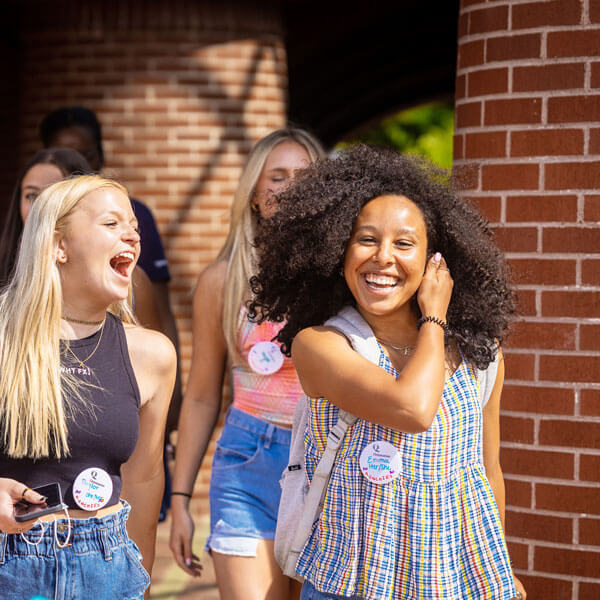 Two students walk and laugh together during Orientation
