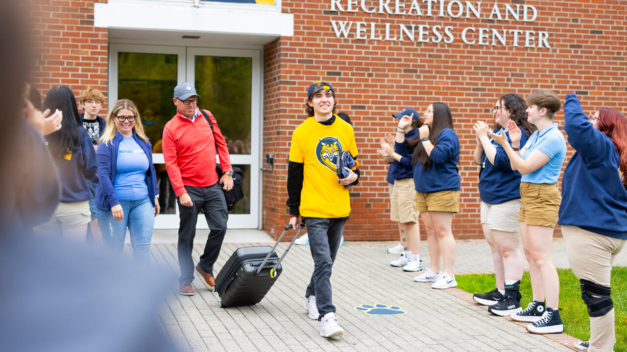 Individual walking out of the Recreation and Wellness Center with a suitcase