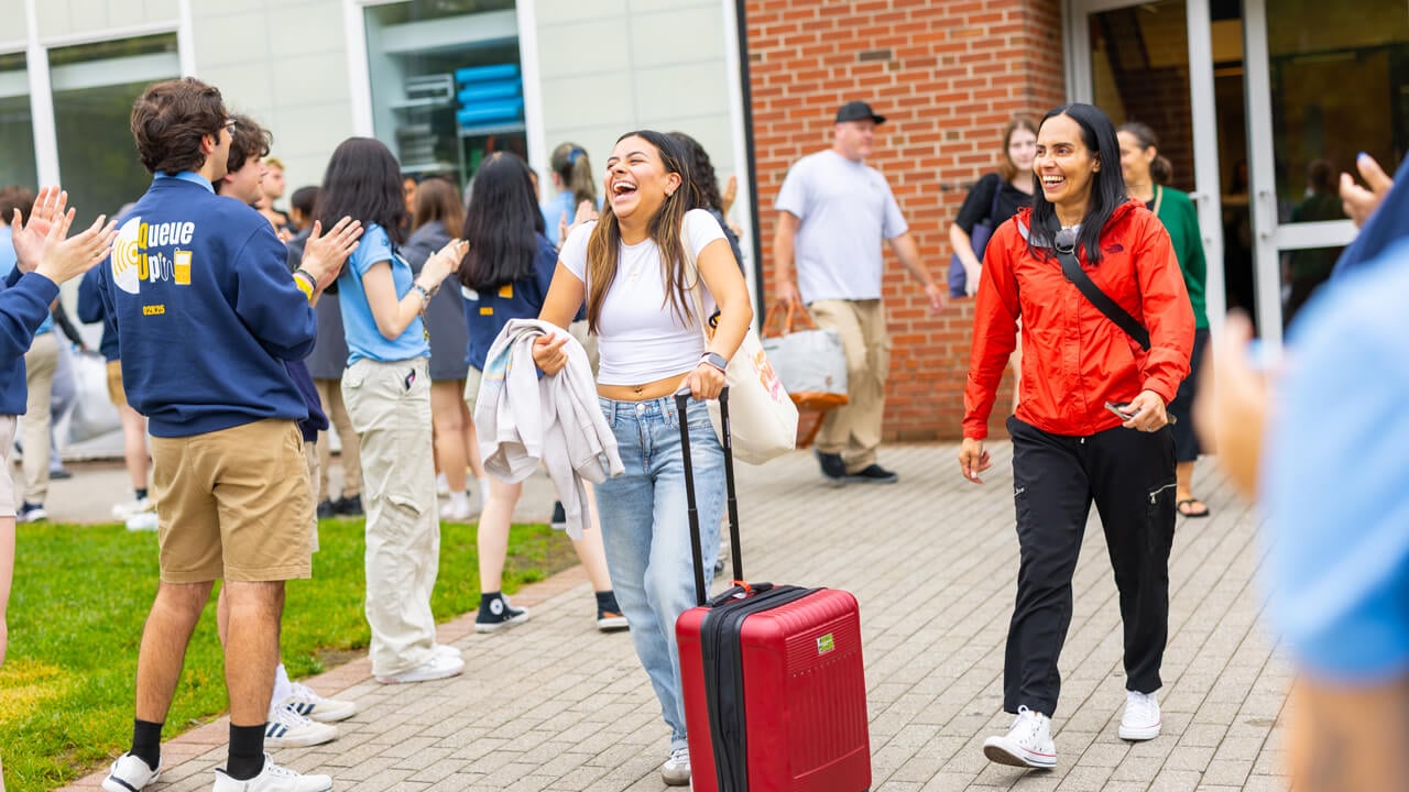 Individual walking out of the Recreation and Wellness Center with a red suitcase