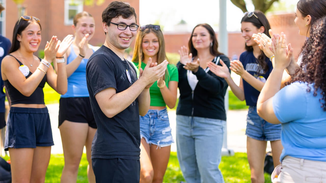 Individuals standing and smiling during Orientation